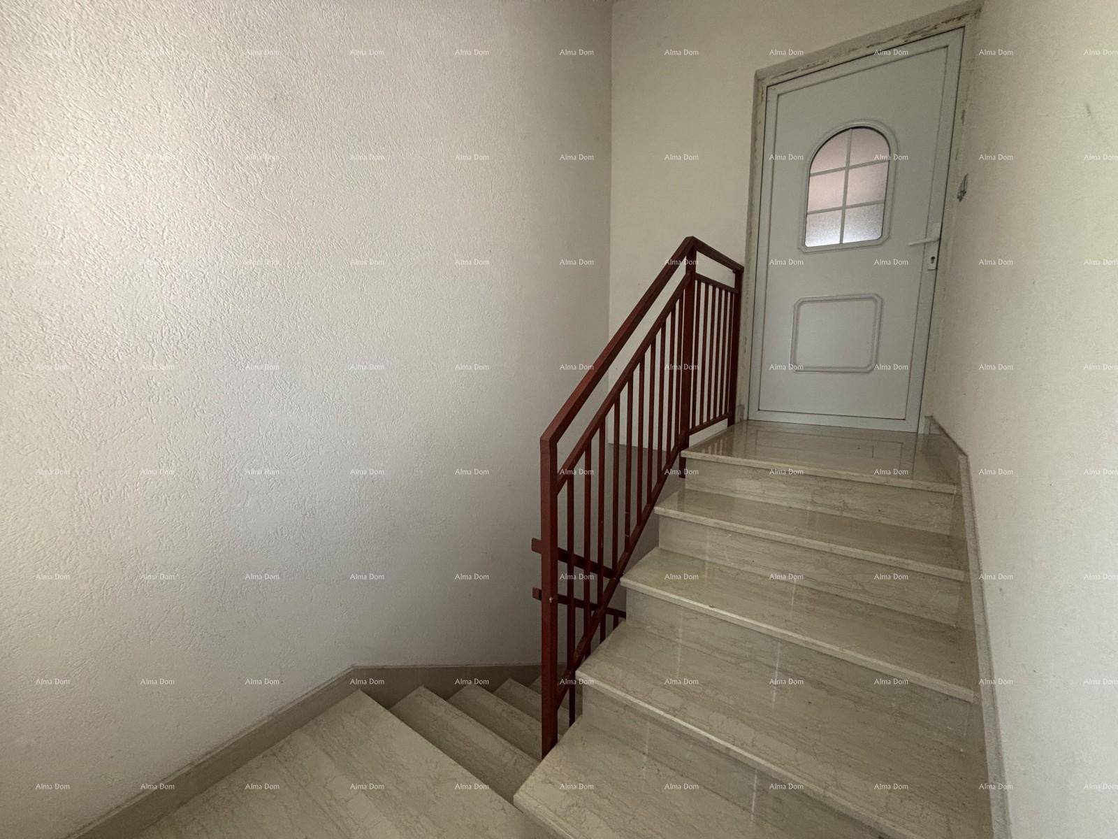 Treppenhaus mit gefliesten Stufen und Metallgeländer, das zu einer oberen Etage führt.
