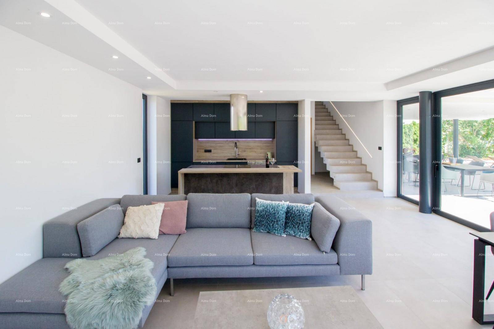 Offener Wohnbereich mit grauem Sofa, integrierter Küche und Zugang zu einer Außenterrasse.