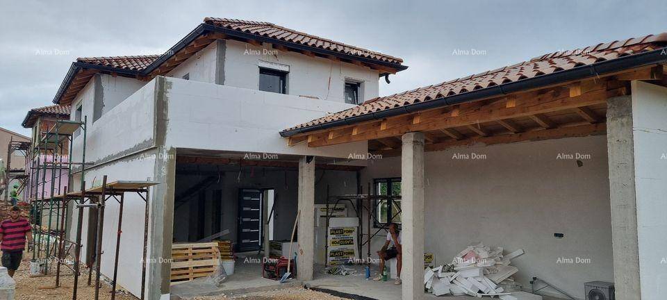 Haus im Bau mit Gerüst und sichtbaren Baumaterialien unter einem Ziegeldach.