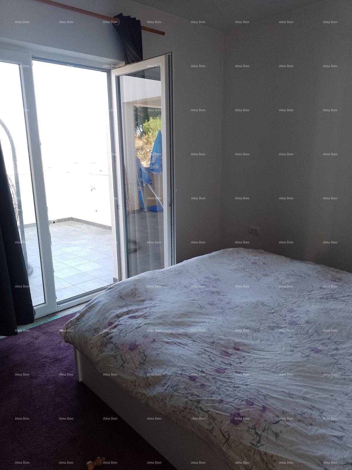 Schlafzimmer mit Doppelbett, Teppichboden und Zugang zu einem sonnigen Außenbereich.