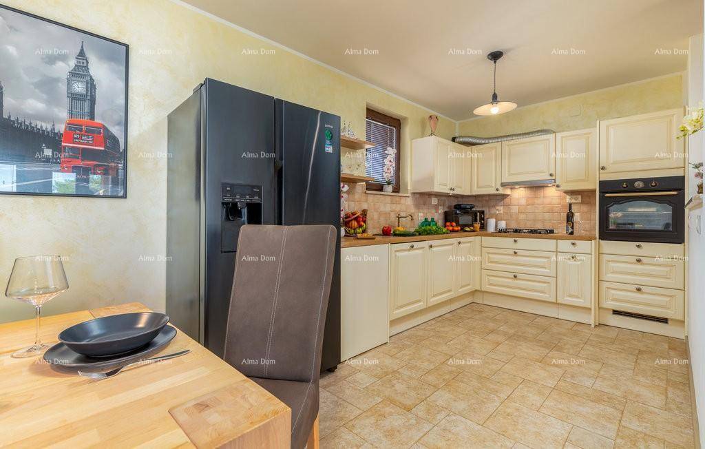 Funktionale Küche mit cremefarbenen Schränken, Holztheke, integrierten Geräten und Fliesenboden.