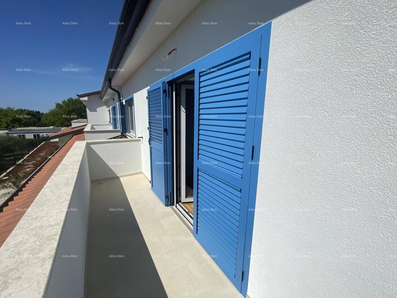 Sonnenverwöhnter Balkon mit blauen Fensterläden und Blick auf die Umgebung, perfekt zum Entspannen.