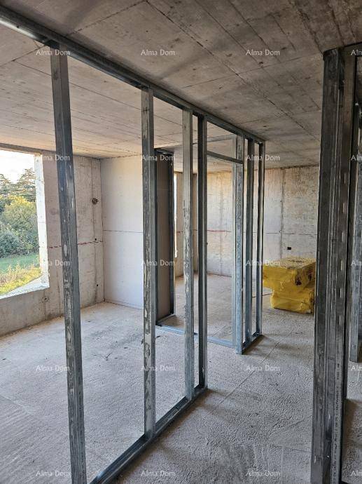 Innenraum im Rohbau mit Betonwänden und Metallständern für Trockenbauwände, Blick ins Grüne.