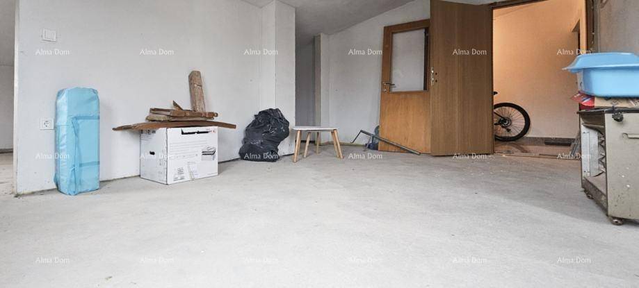 Unfertiger Innenraum mit Betonboden und einer Holztür, der noch ausgebaut werden muss.