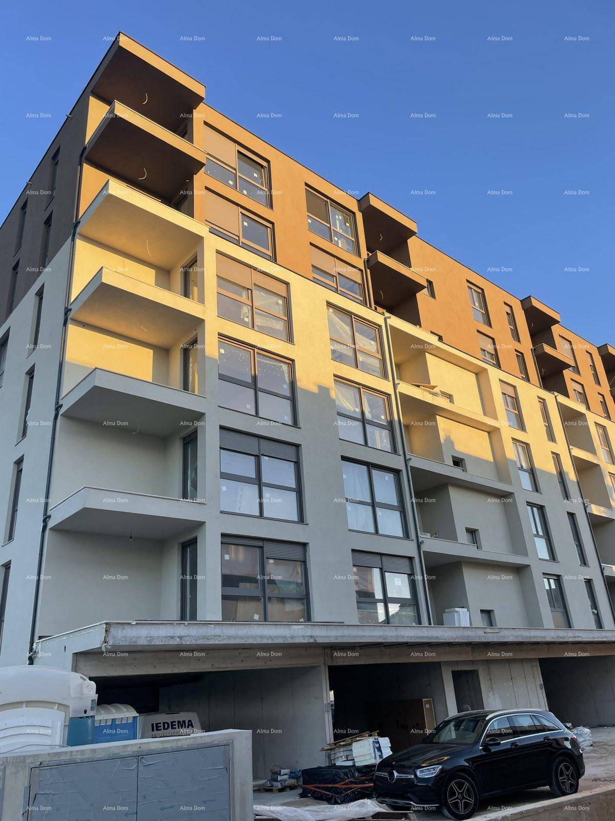Nahaufnahme der Fassade eines modernen Neubaus mit Balkonen und großen Fensterfronten im warmen Abendlicht.