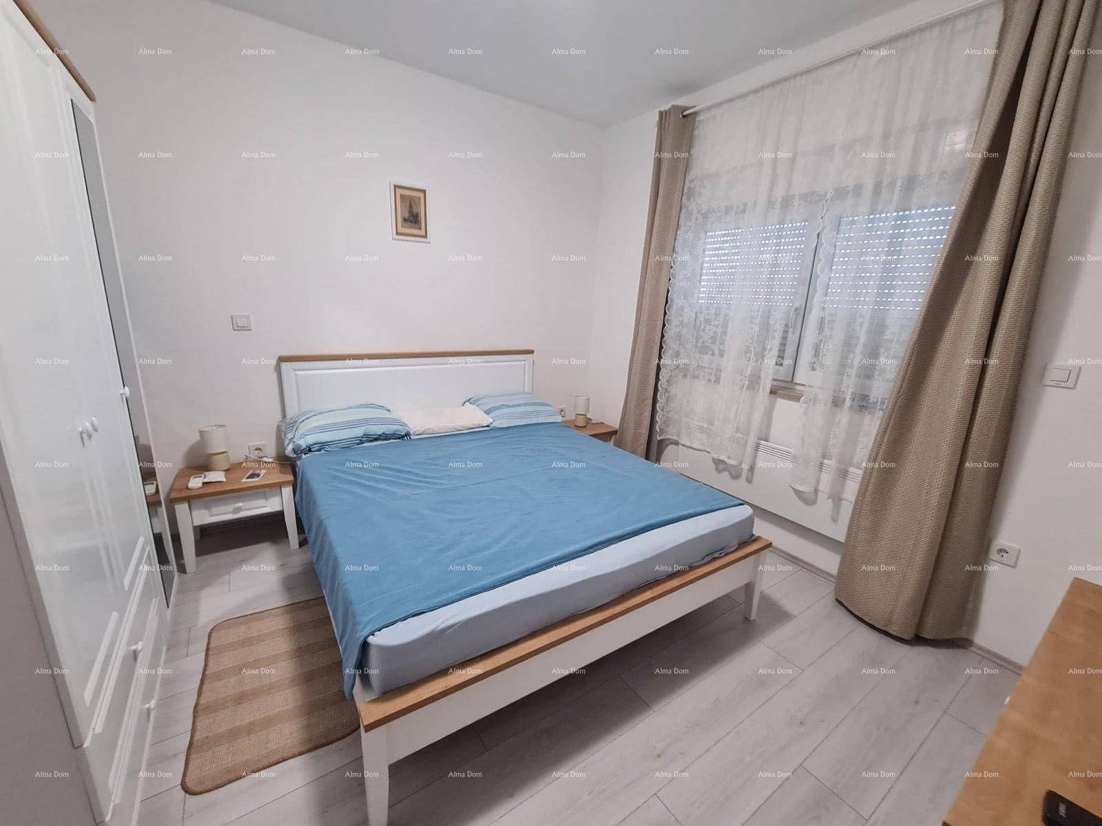 Schlafzimmer mit weißem Kleiderschrank, Doppelbett mit blauer Bettwäsche und hellem Holzboden.