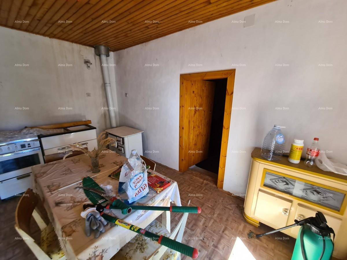 Einfache Küche mit Holztisch, alten Möbeln und Holzdecke, bereit zur Renovierung.