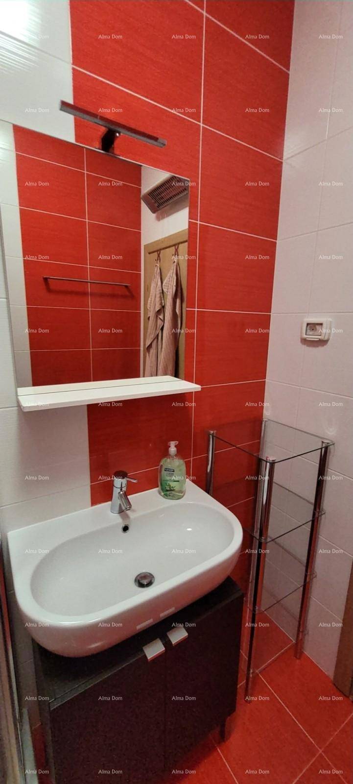 Badezimmer mit modernem Waschbecken, Spiegel und dekorativen rot-weißen Wandfliesen.