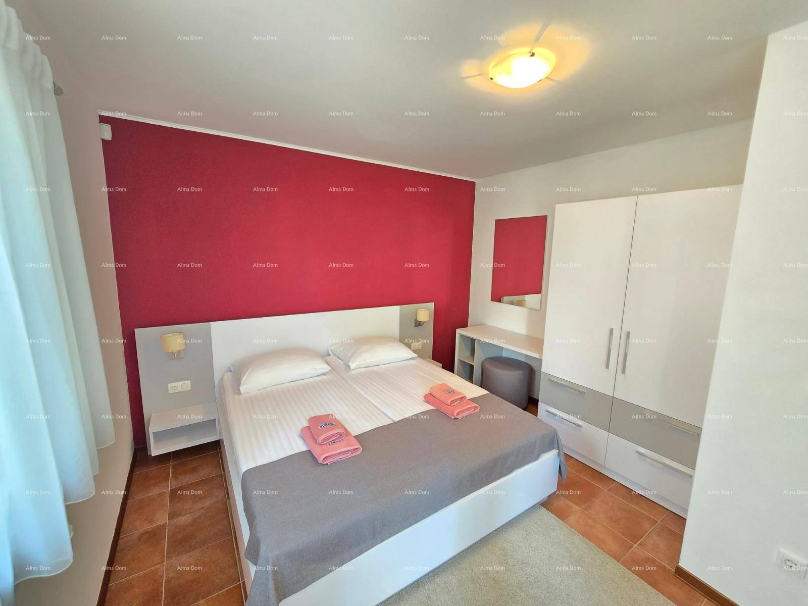 Schlafzimmer mit Doppelbett, Kleiderschrank und einer roten Akzentwand.