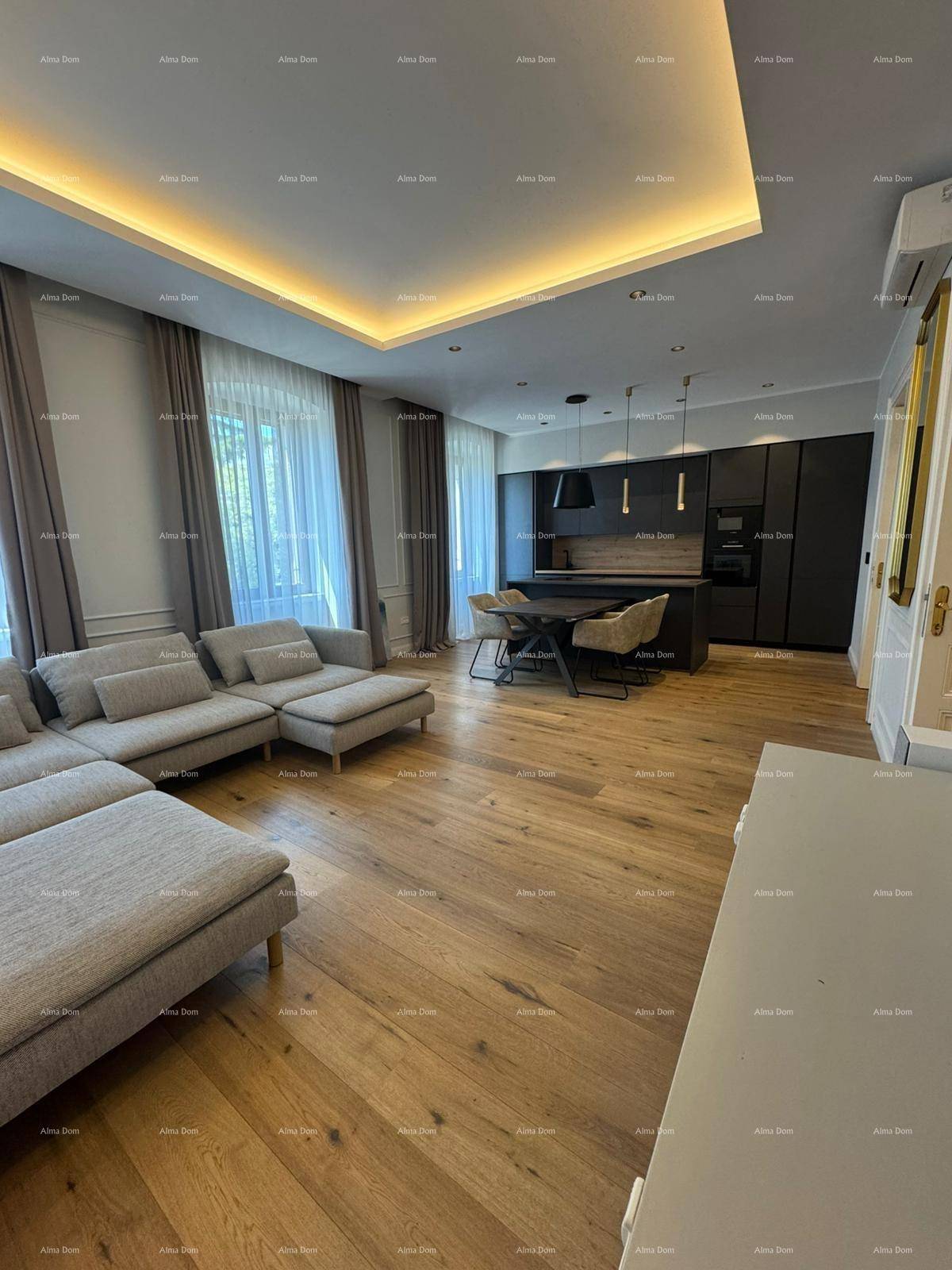 Heller Wohnbereich mit Holzboden, großer Couch und Blick auf die moderne Küche.