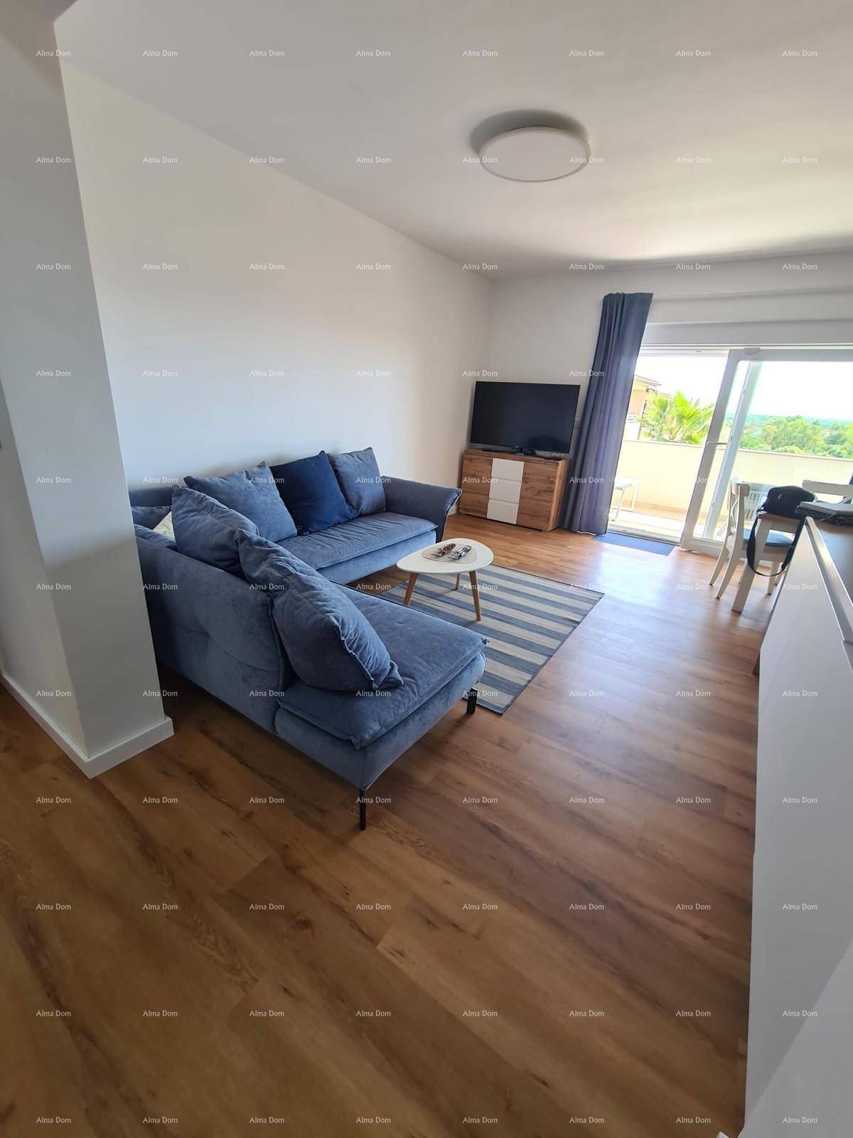 Gemütliches Wohnzimmer mit blauem Ecksofa, Fernseher und direktem Zugang zu einem sonnigen Außenbereich.