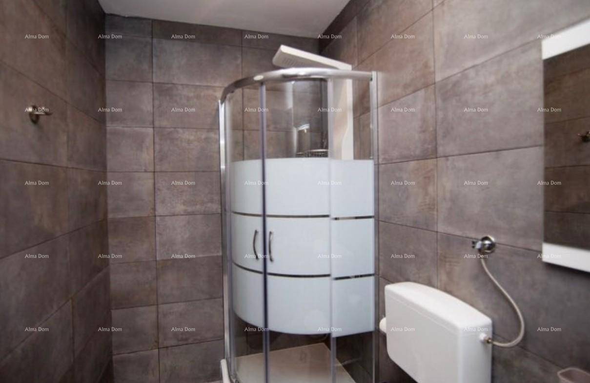 Modernes Badezimmer mit Duschkabine, Toilette und grauen Fliesen an Wänden und Boden.
