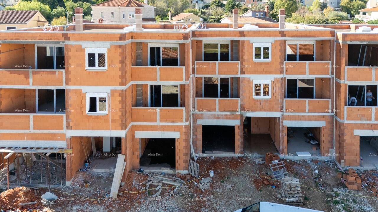 Frontansicht des im Bau befindlichen Gebäudes mit mehreren Wohneinheiten und Garagenöffnungen.