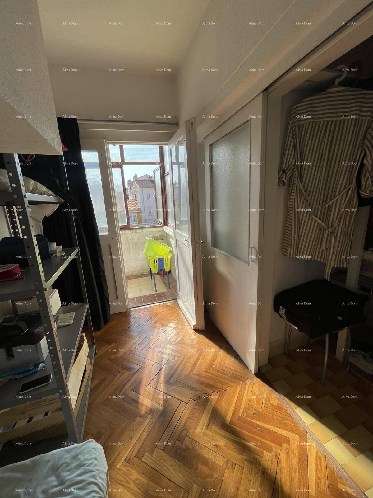 Schlafzimmer mit Holzboden, Kleiderschrank und Balkonzugang, gut beleuchtet.