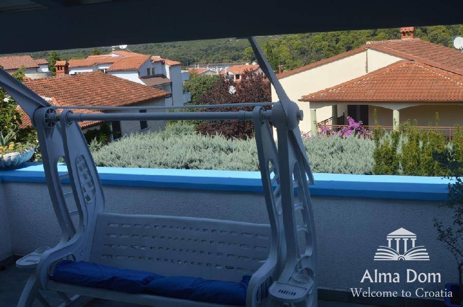 Balkon mit Schaukelbank und Blick über die Dächer der Nachbarschaft.