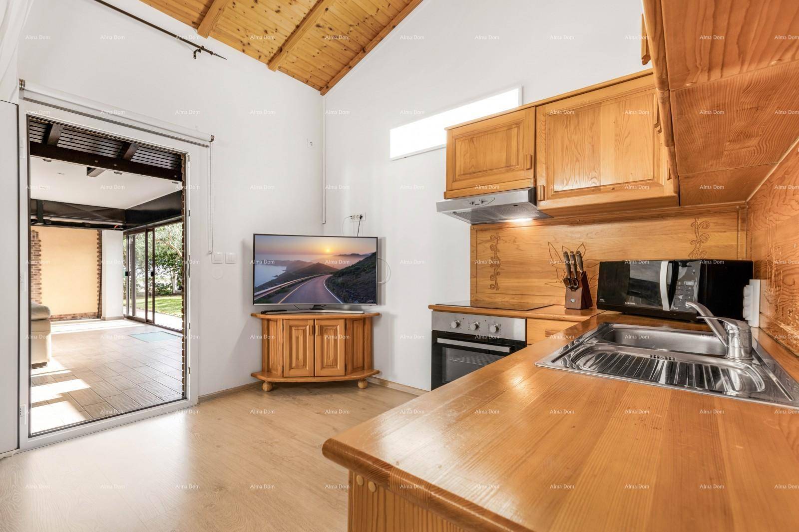 Funktionale Holzküche mit Essbereich, Fernseher und Zugang zu einem Außenbereich.