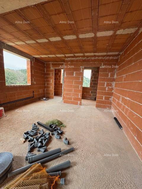 Großer Rohbau-Innenraum mit Ziegelwänden, mehreren Fensteröffnungen und Baumaterialien am Boden.