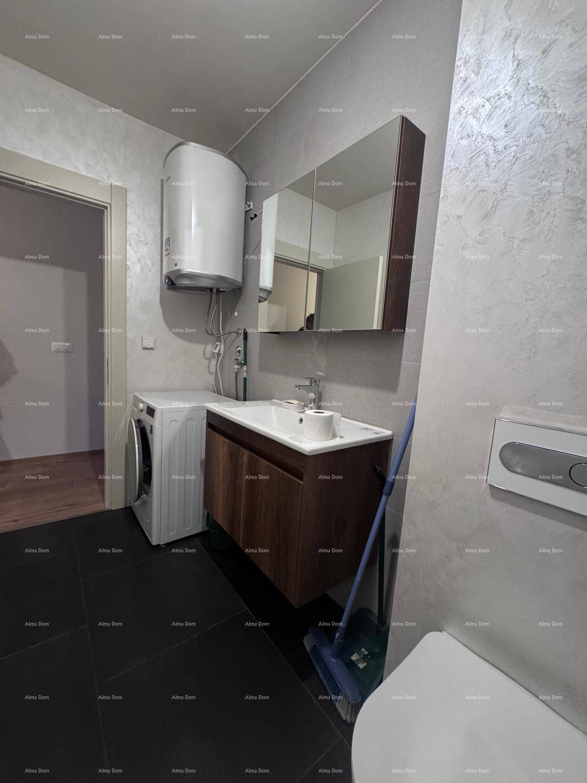 Badezimmer mit Waschmaschine, modernem Waschbeckenunterschrank und Toilette, auf dunklen Fliesen.