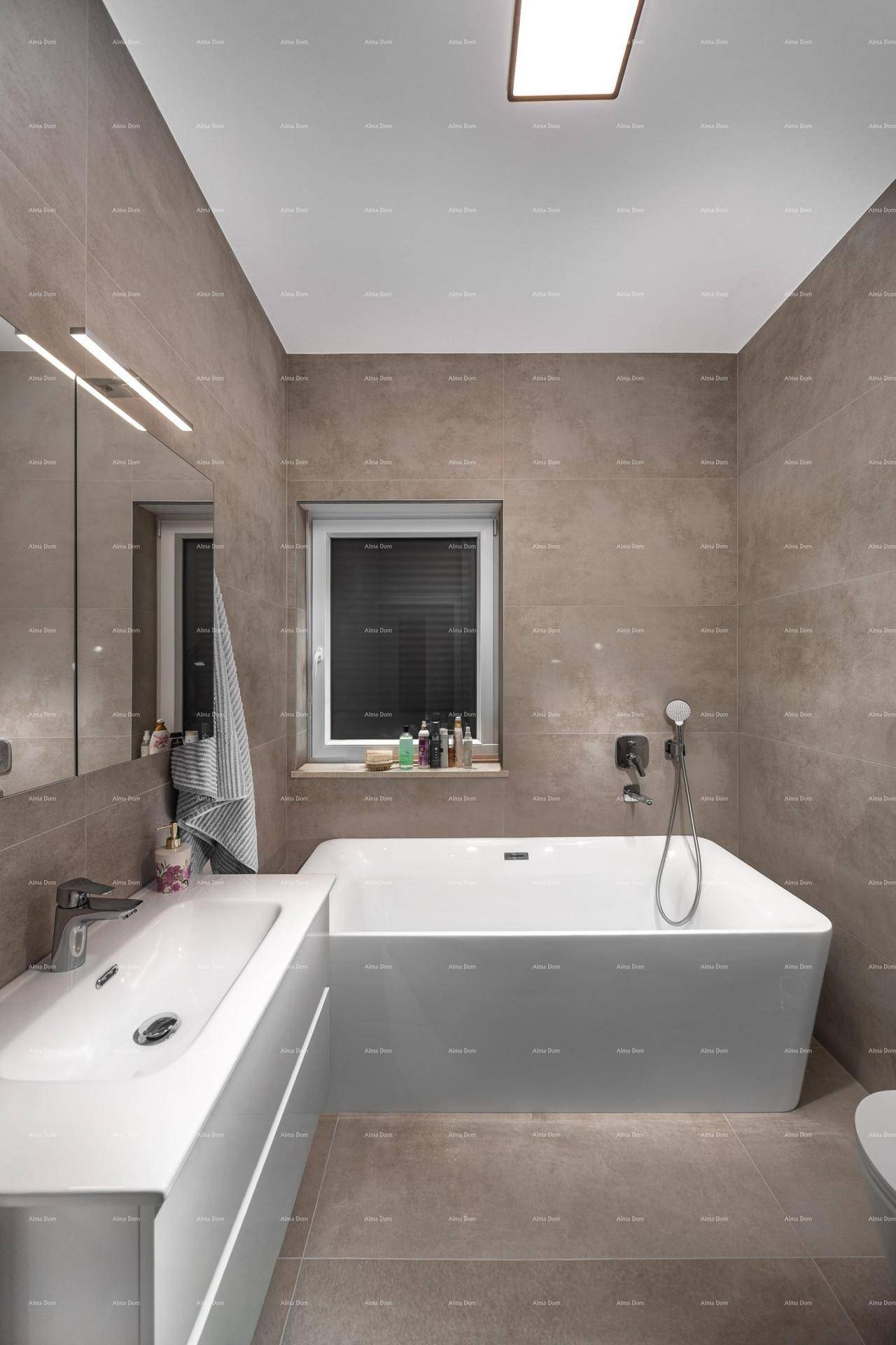 Modernes Badezimmer mit Badewanne, schwebendem Waschtisch und Fenster, gefliest in Grautönen.