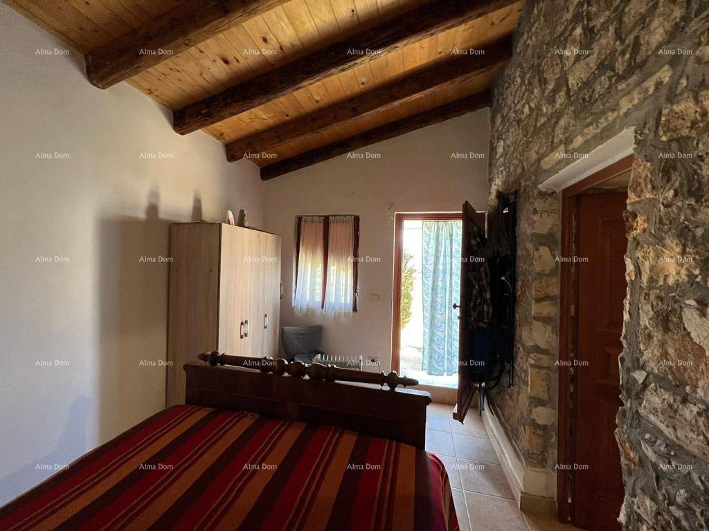 Rustikales Schlafzimmer mit Holzbalkendecke, Steinwand und Zugang zum Außenbereich.
