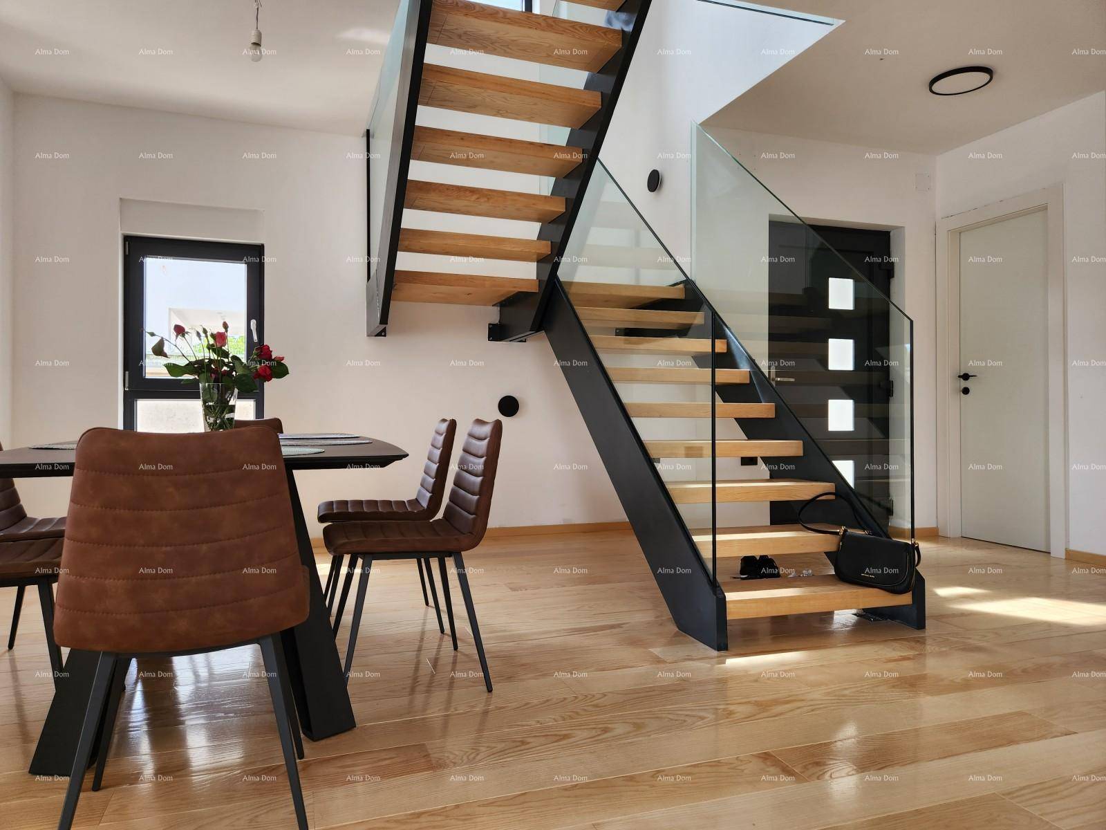 Moderner Essbereich mit Holzboden und einer eleganten Treppe mit Glasgeländer, die die Etagen verbindet.