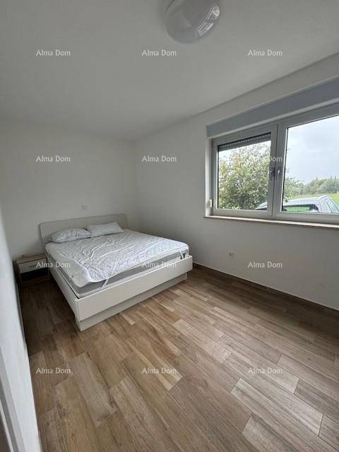 Helles Schlafzimmer mit Holzfußboden, einem Doppelbett und Blick ins Grüne.