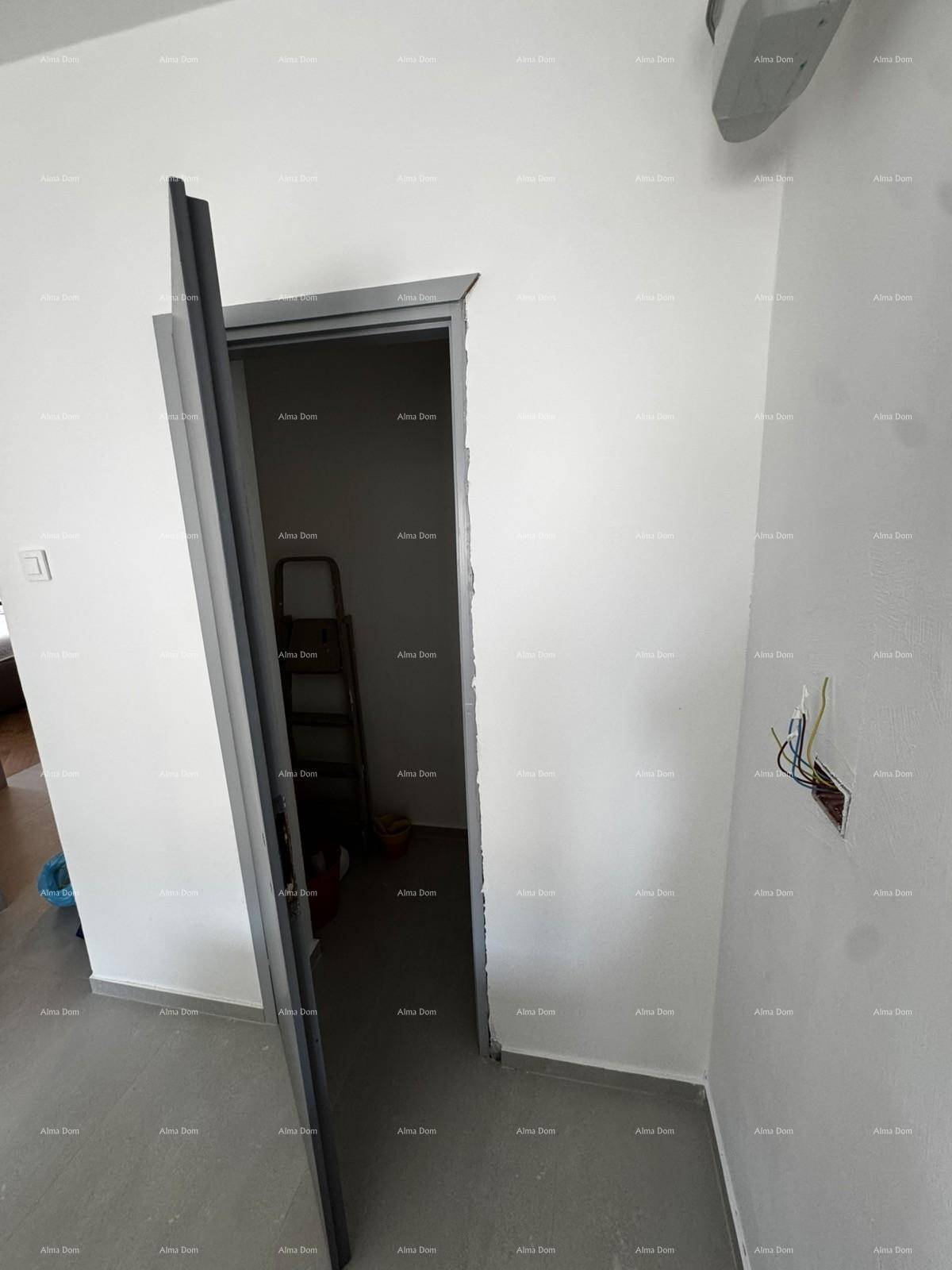 Innenraum mit offener Tür, der einen Blick in einen weiteren Raum mit Leiter freigibt.