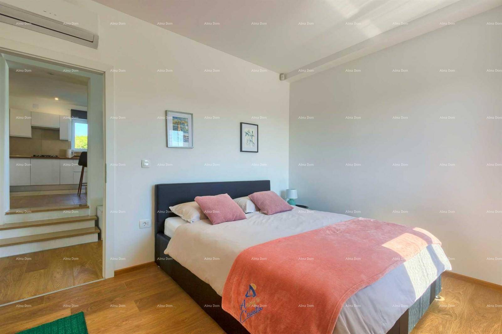 Schlafzimmer mit Holzboden, Doppelbett und Blick in den angrenzenden Küchenbereich.