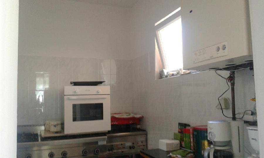 Funktionale Küche mit einem Backofen, Kochfeld und einem kleinen Fenster, das Tageslicht spendet. 