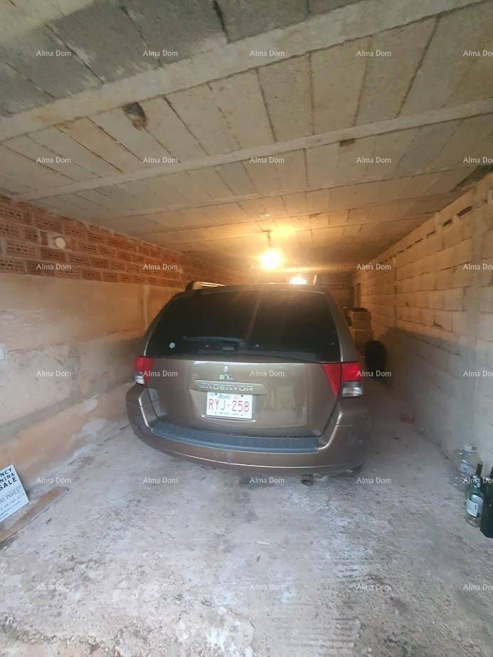 Einfache Garage mit Betonwänden und einem geparkten Auto.