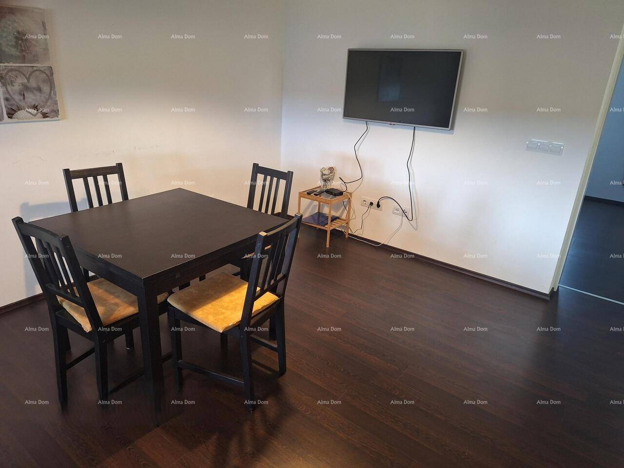 Essbereich mit dunklem Holztisch und Stühlen, ergänzt durch einen an der Wand montierten Fernseher.
