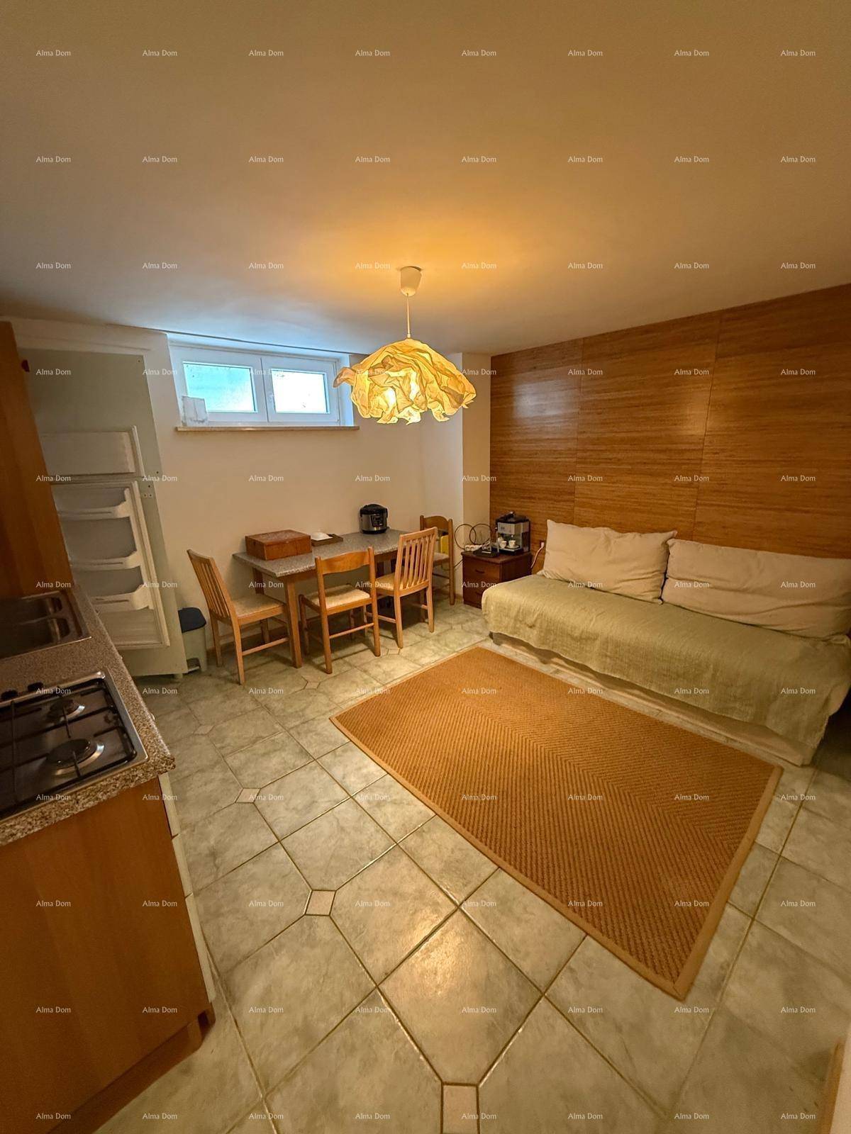 Offener Wohn- und Essbereich mit Küchenzeile, Fliesenboden und Holzvertäfelung an einer Wand.