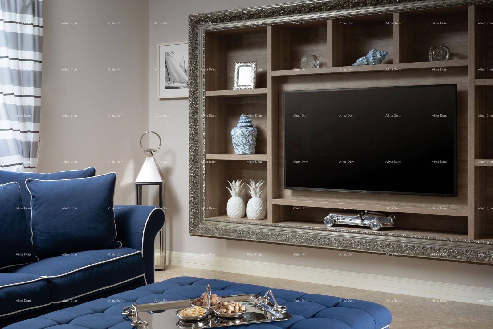 Detailansicht des Wohnzimmers mit blauem Polsterhocker und integriertem TV-Regal.
