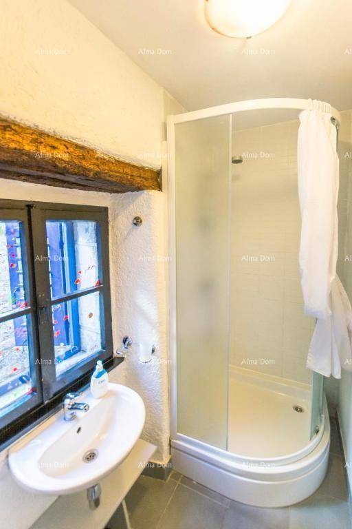 Badezimmer mit Waschbecken und einer Duschkabine, daneben ein Fenster.