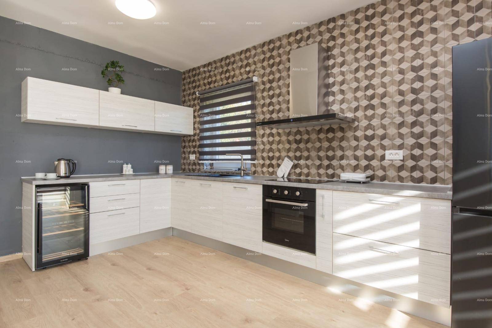 Moderne Küche mit weißen Schränken, Induktionskochfeld und auffälliger geometrischer Wandgestaltung.