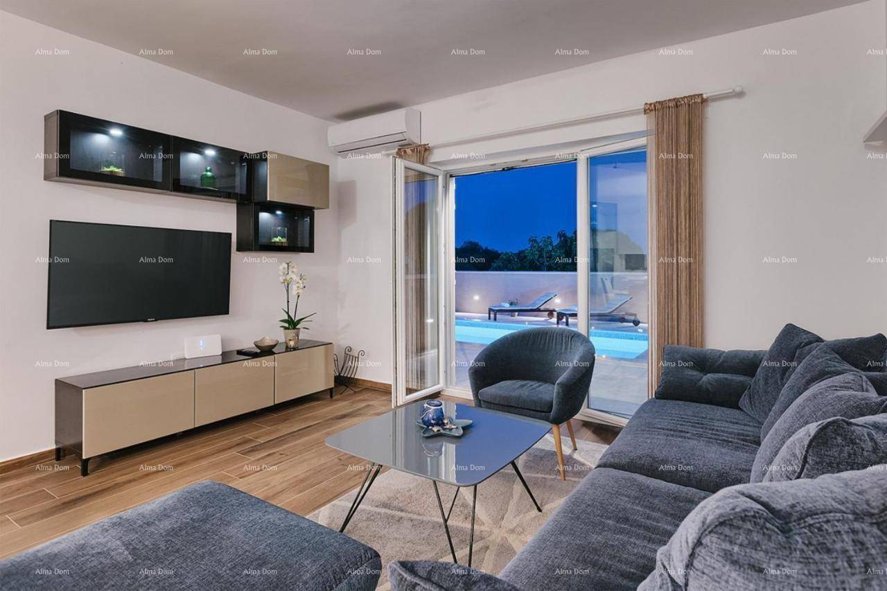 Modernes Wohnzimmer am Abend mit indirekter Beleuchtung und Blick auf den beleuchteten Pool.