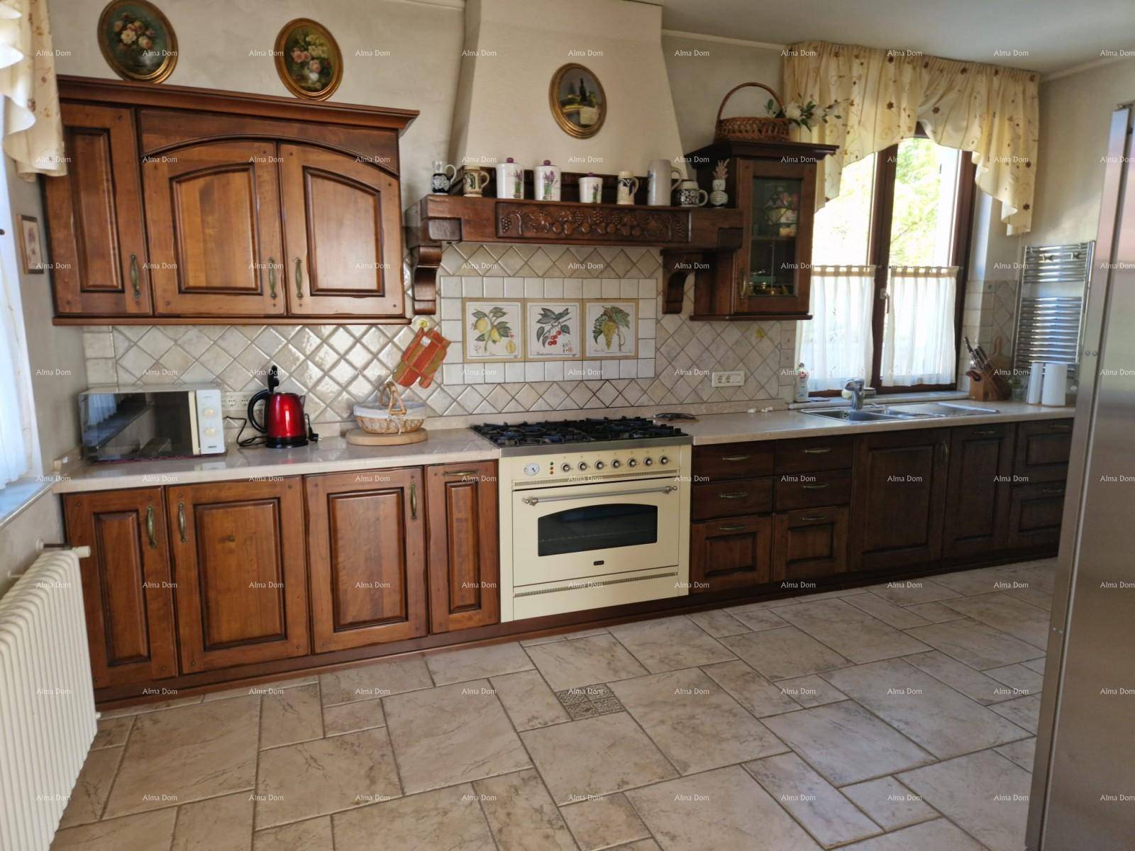 Traditionelle Holzküche mit Gasherd, Fliesenboden und Fenster mit Vorhängen.