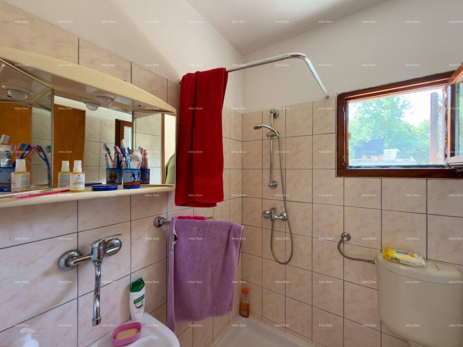 Badezimmer mit Duschwanne, WC und Fenster, hell gefliest und funktional ausgestattet.