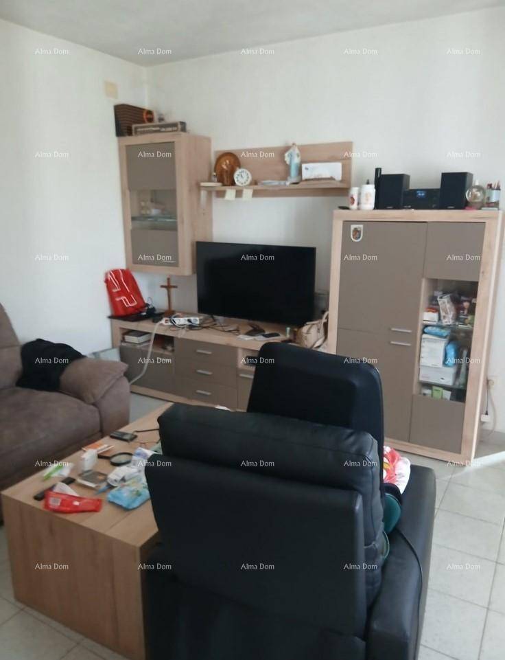 Gemütliches Wohnzimmer mit Sofa, Fernseher und verschiedenen Möbelstücken auf hellem Fliesenboden.