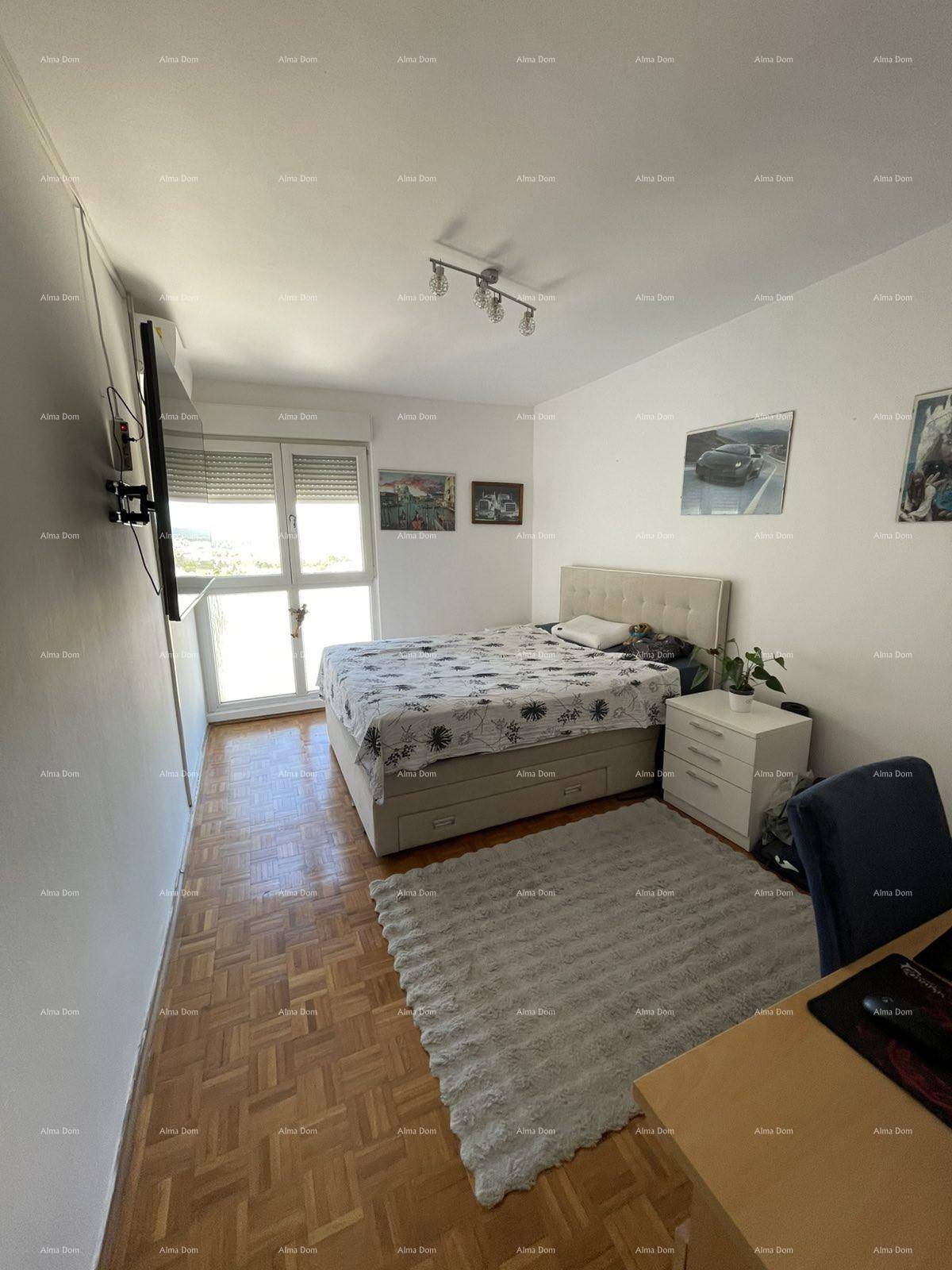 Helles Schlafzimmer mit Parkettboden, Doppelbett und Zugang zu einem Balkon.