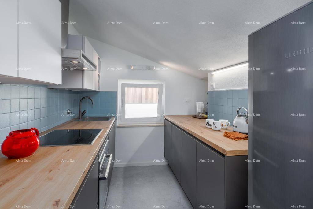Funktionale Küche mit blauen Fliesen, Holzarbeitsplatten, Fenster und modernen Geräten.