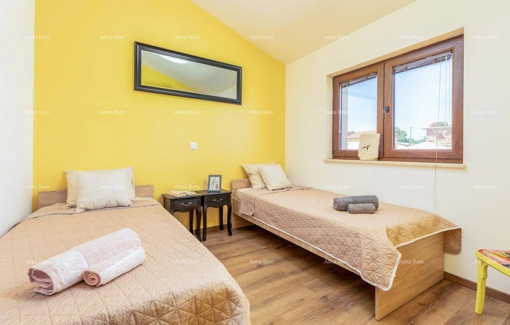 Freundliches Schlafzimmer mit zwei Einzelbetten, gelber Akzentwand, Holzboden und großem Fenster.