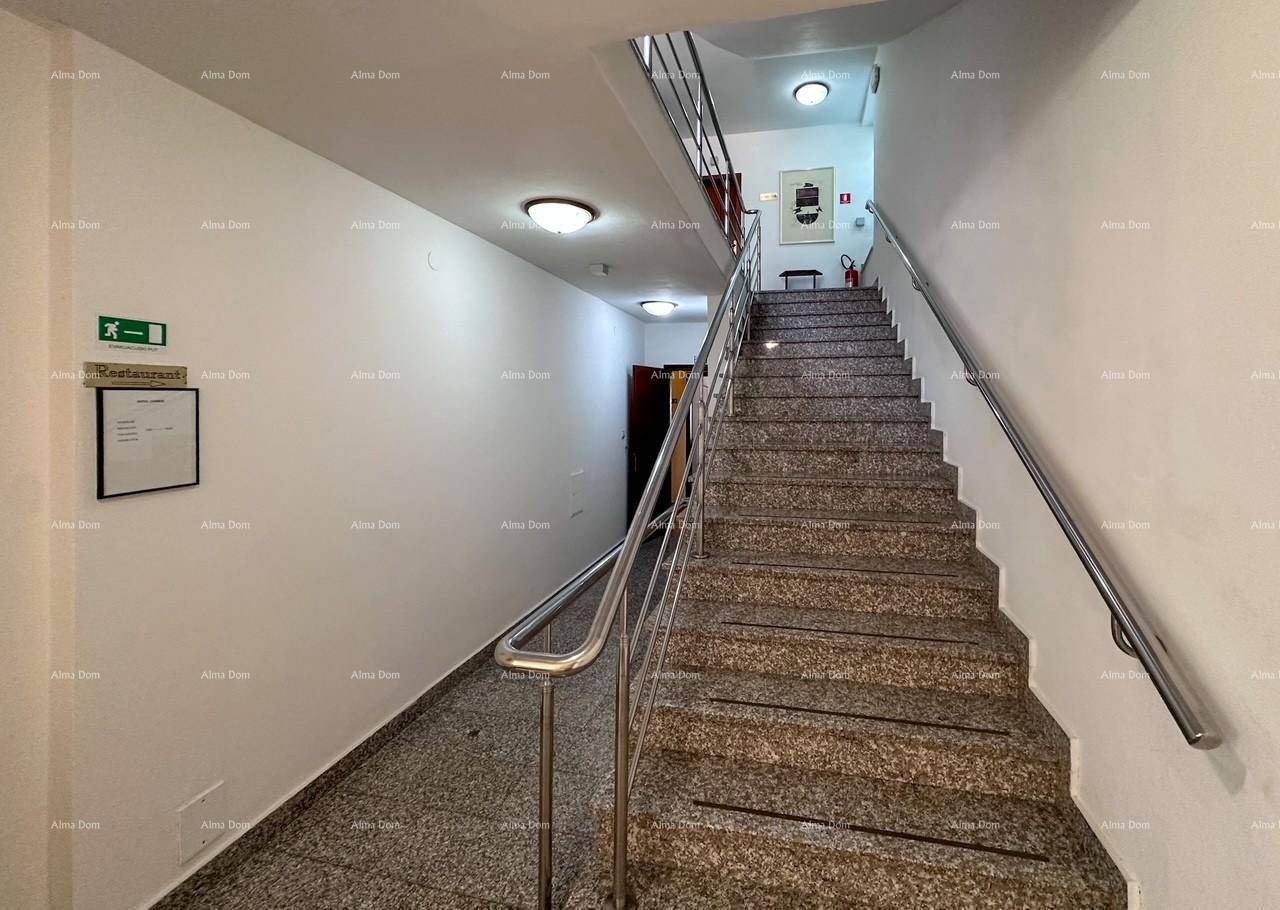 Treppenhaus mit Granitstufen und Metallgeländer, das zu den oberen Etagen führt, neben einem Flur.