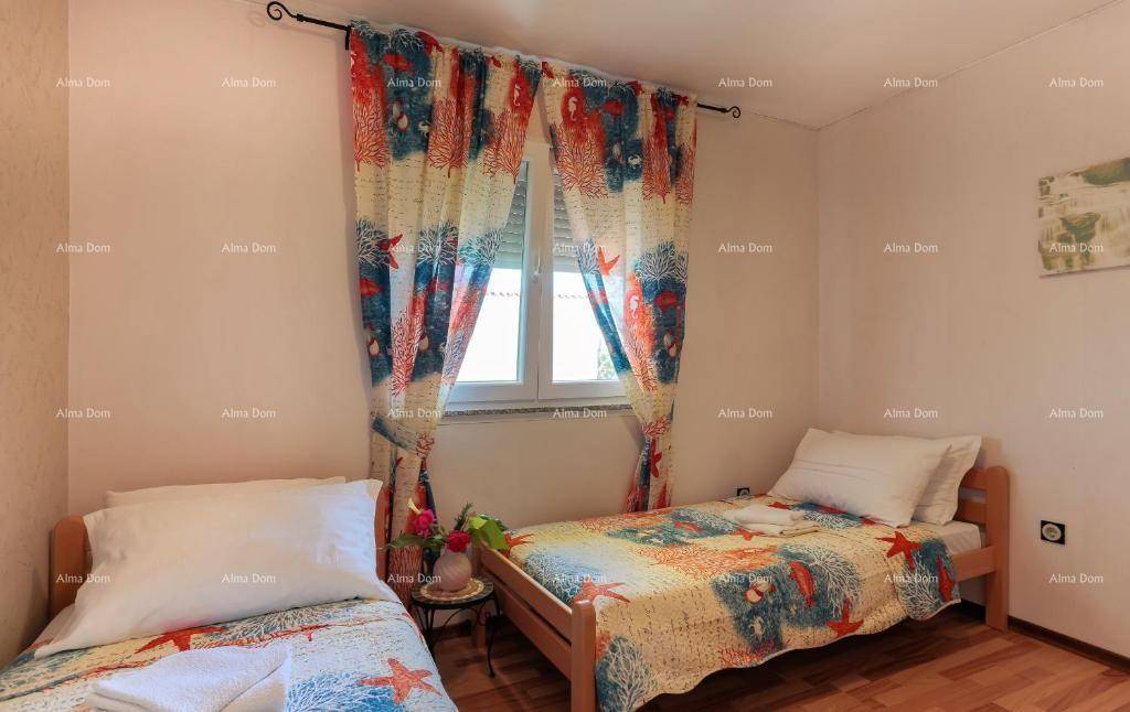 Schlafzimmer mit zwei Einzelbetten, Holzboden und farbenfrohen Vorhängen.