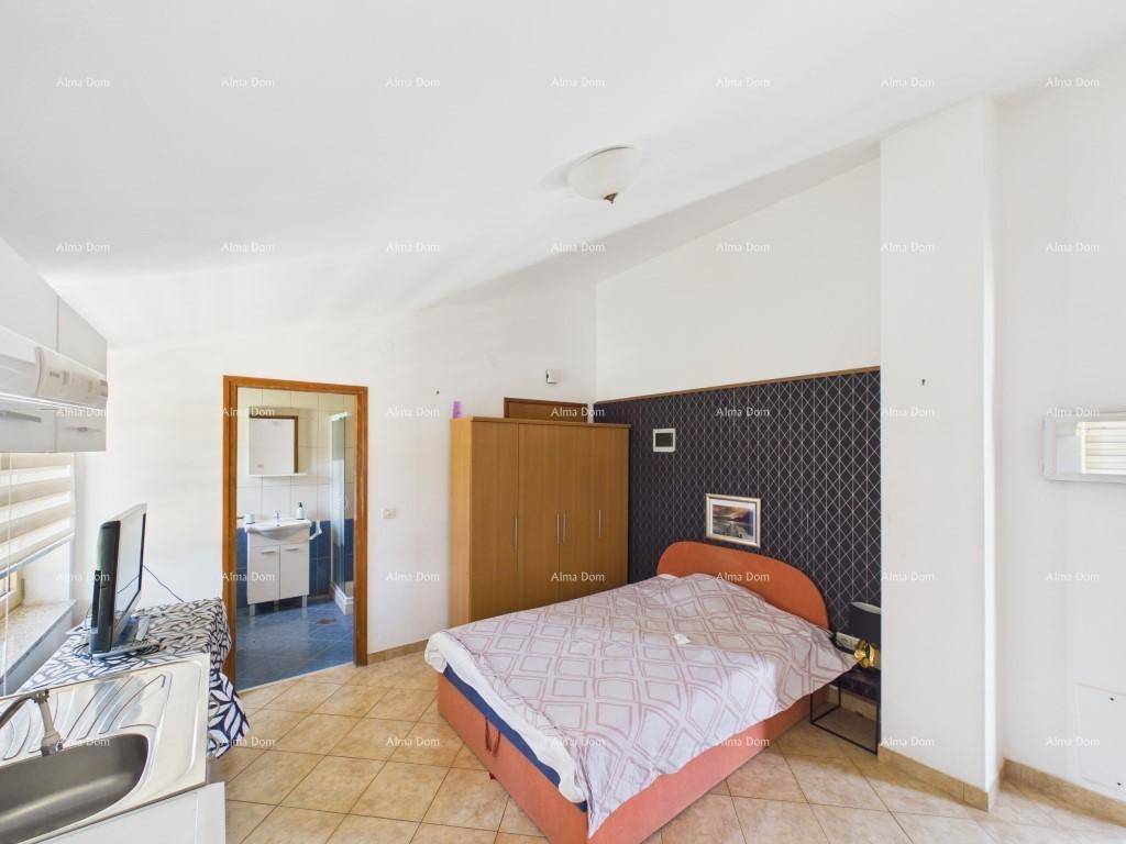 Schlafbereich im Studio-Apartment mit Doppelbett, Kleiderschrank und Zugang zu einem Badezimmer.
