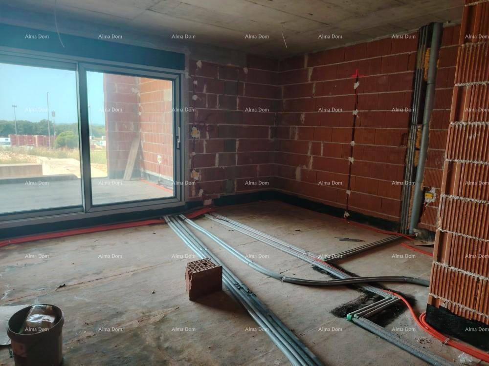 Innenraum im Rohbau mit Ziegelwänden, Betonboden und einer großen Schiebetür, die viel Licht hereinlässt.