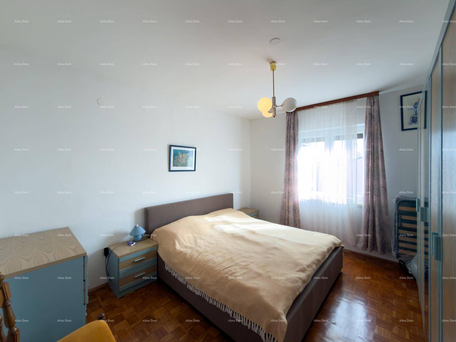 Helles Schlafzimmer mit Doppelbett, Parkettboden und Fenster mit Vorhängen.