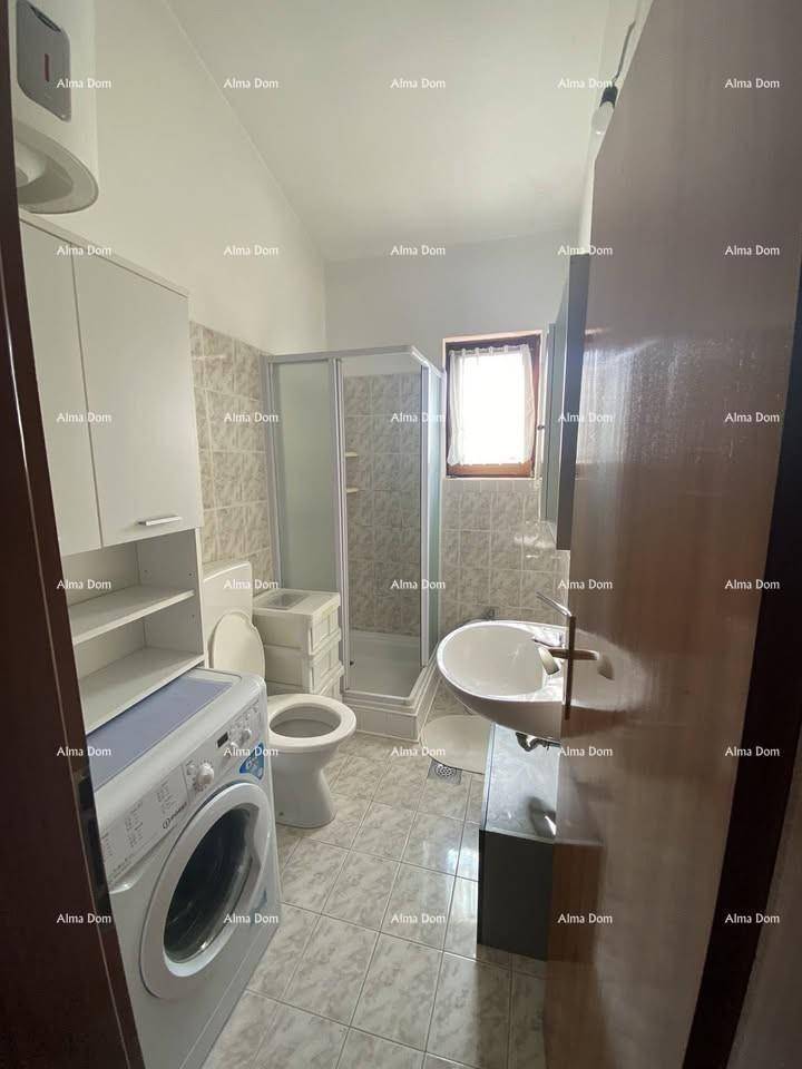 Badezimmer mit Dusche, Waschbecken, Toilette und Waschmaschine, komplett gefliest.
