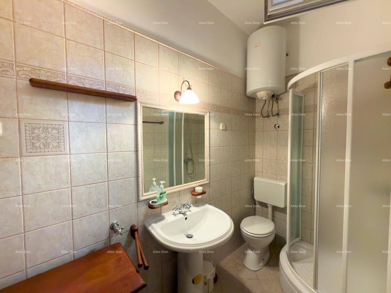 Badezimmer mit Dusche, Waschbecken, Toilette und beigen Fliesen.