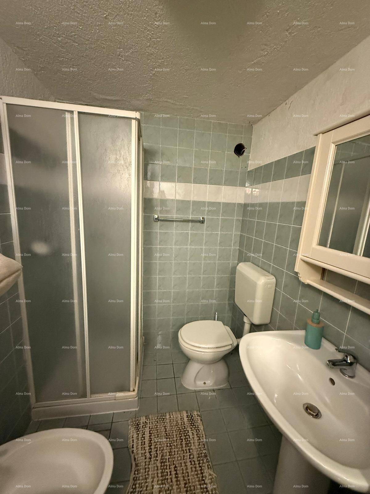 Badezimmer mit Duschkabine, WC, Bidet und Waschbecken, ausgestattet mit hellgrünen Fliesen.